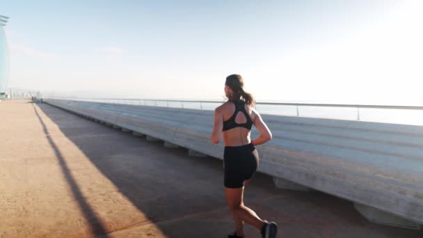 Sportvrouw joggen in de buurt van de haven in de ochtend — Stockvideo