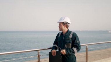 Denetim sırasında miğferli liman müfettişi ve gemi teftiş listesini dolduruyor.