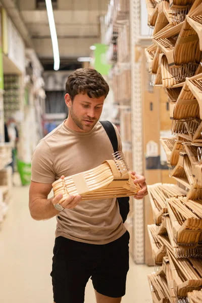 Hombre tomando pila de perchas en la tienda — Foto de Stock