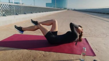 Sporcu kadın sabah karın kası egzersizi yapıyor.