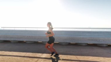 Spor kadını sabah limana yakın koşuyor.