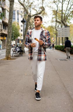Elinde churros tatlısıyla sokakta yürüyen adam.