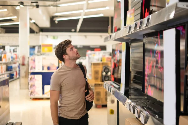 Hombre comprador examinar TV en estante — Foto de Stock