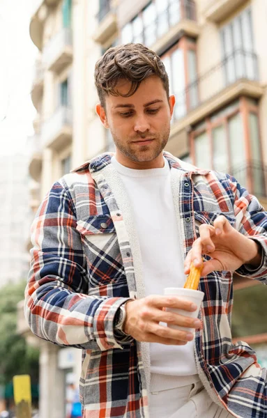 Человек ест сладкие чуррос на городской улице — стоковое фото