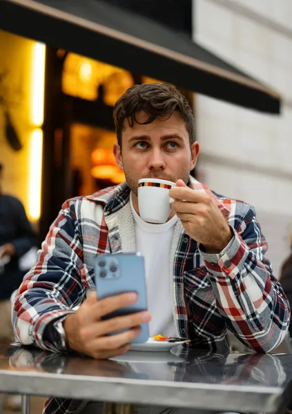 Модный человек пьет кофе в уличном кафе — стоковое фото