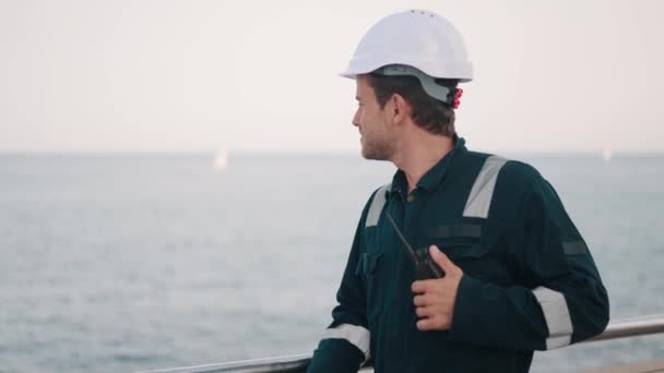 Joven hombre guapo trabajador portuario con walkie-talkie en mano que controla el proceso de trabajo en el puerto de envío — Vídeos de Stock