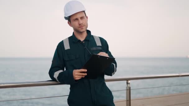 港口检查员手持剪贴板和vhf收音机站在海港站，用核对表作笔记 — 图库视频影像