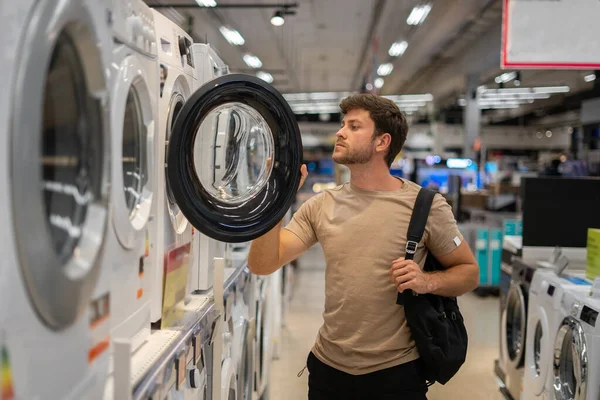 Comprador masculino olhando dentro da máquina de lavar roupa — Fotografia de Stock