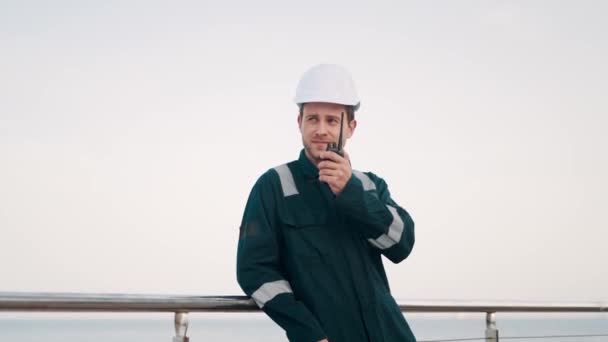 Havenwerker aan het praten op walkie-talkie radio terwijl hij vrachtlogistiek controle doet in de zeehaven — Stockvideo
