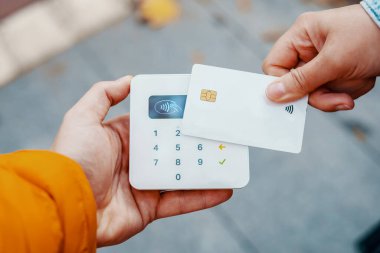 Kredi kartı ve NFC terminali ile ödeme yapan anonim bir kişi ekin