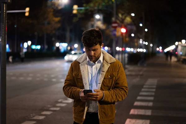 Человек просматривает смартфон в ночном городе — стоковое фото