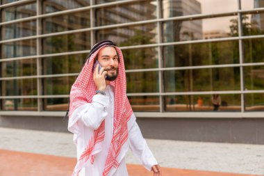 Sakallı Arap adam akıllı telefon konuşması yapıyor.