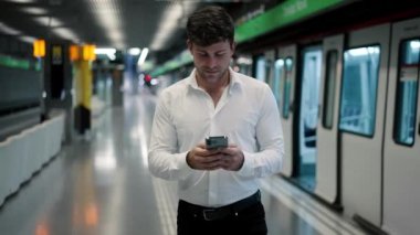 İş adamı metro istasyonunda akıllı telefon kullanıyor.