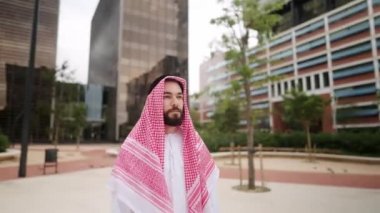 Geleneksel Suudi kıyafetleri içinde kendine güvenen yakışıklı bir adam boş meydanda tek başına dikiliyor.