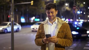 Gece sokakta akıllı telefon kullanan bir adam.