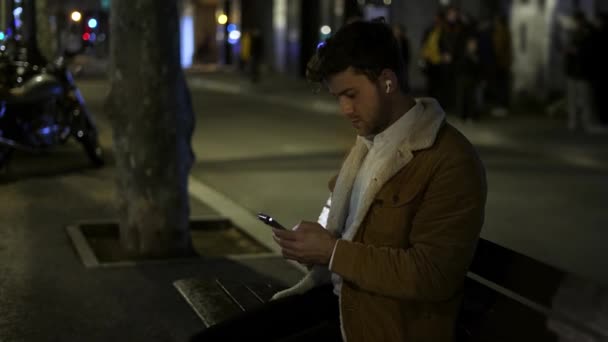 Férfi használ okostelefon padon éjjel — Stock videók