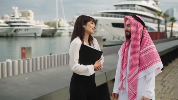 Smiling saudi businessman talking with female professional yacht broker before buying boat in port — Vídeos de Stock