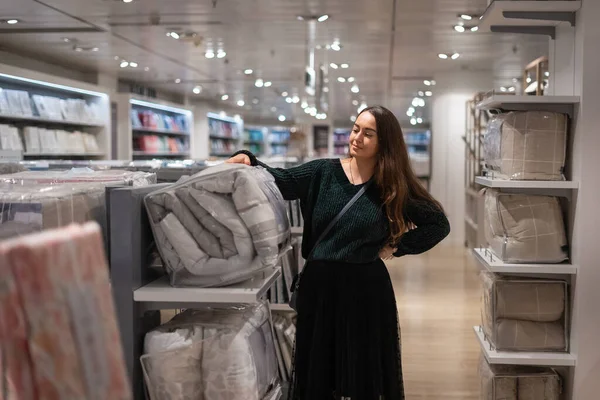 Cliente feminino escolhendo edredão na loja — Fotografia de Stock
