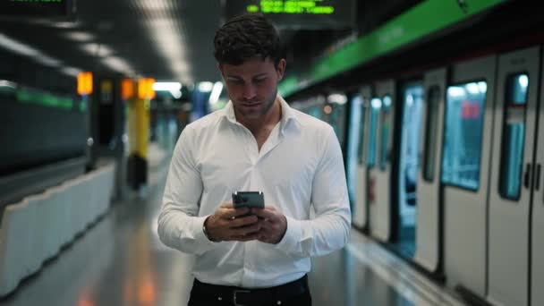 Positieve mannelijke manager met mobiele telefoon lopen op het platform — Stockvideo