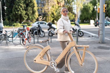 Modern caddede yürüyen kadın bisikletçi.