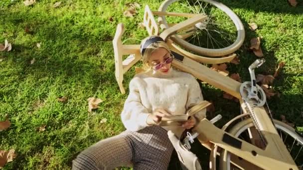 나무로 된 친환경 자전거를 타고 책을 읽고 있는 여성 — 비디오