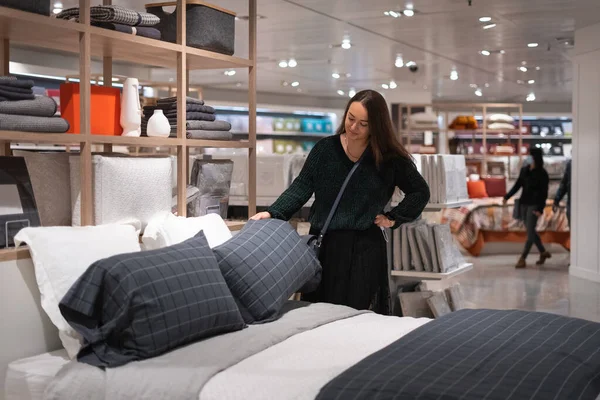 Woman examining pillows on bed in mall Stock Photo