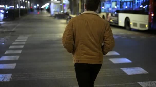 Mężczyzna przechodzący przez ulicę na ciemnej ulicy — Wideo stockowe