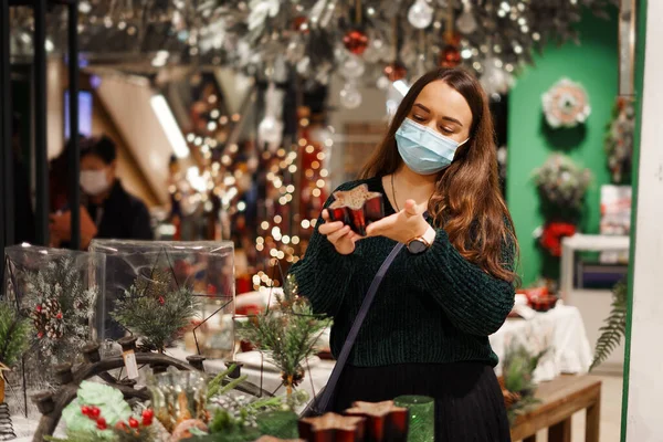 Beyaz maskeli mutlu genç kadın kış tatili alışveriş turunun tadını çıkarıyor.