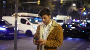 Gece sokakta akıllı telefon kullanan bir adam.