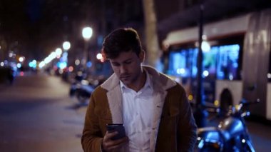 Sokakta yürüyen cep telefonu olan bir erkek.