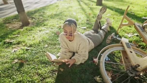 Γυναίκα ανάγνωση βιβλίο κοντά στο ξύλινο ποδήλατο στο ξέφωτο — Αρχείο Βίντεο