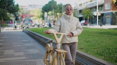 Parkta yürüyen bisikletli bir kadın.