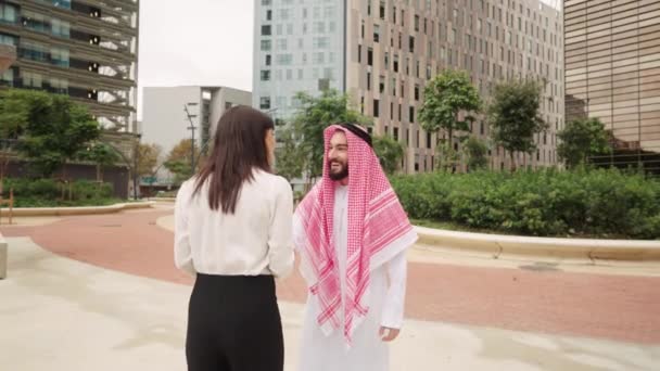 Glimlachende Arabische zakenman begroet vrouwelijke zakenpartner buiten voor contractonderhandelingen — Stockvideo