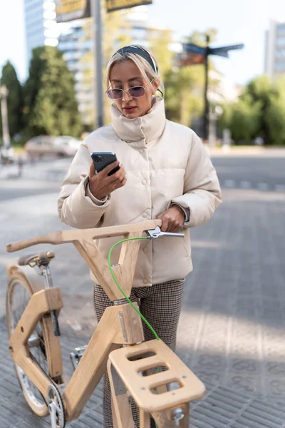 Kobieta rowerzysta za pomocą telefonu komórkowego na ulicy — Zdjęcie stockowe