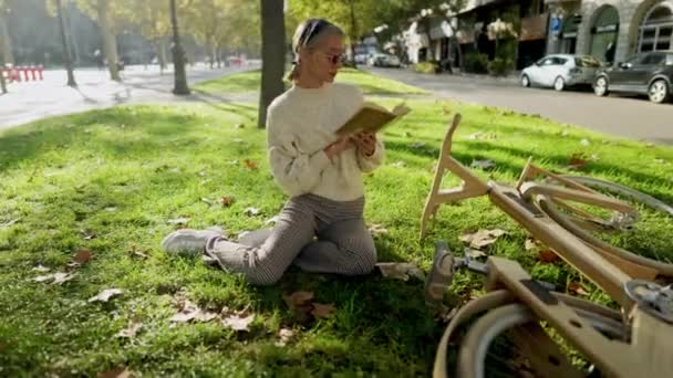 Kobieta z drewnianym rowerem ekologicznym czyta książkę — Wideo stockowe