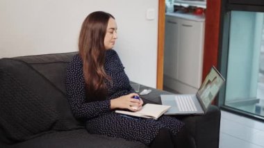 Kanepede genç bir kadın çevrimiçi danışmanlık sırasında doktorla ilaç ya da tedavi planını tartışıyor.