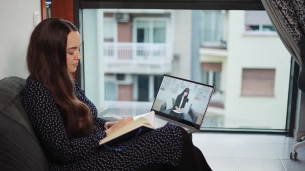 Young woman receiving online psychoterapy consultation while sitting on sofa with laptop at home — Stockvideo