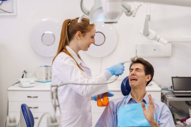 Neşeli dişçi korkmuş hastayı tedavi ediyor.