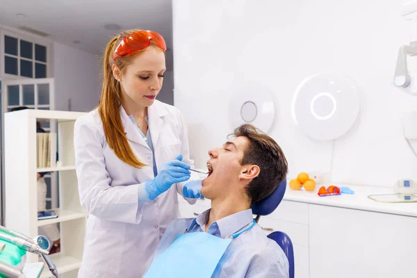 Dentiste gingembre examinant les dents du patient masculin — Photo