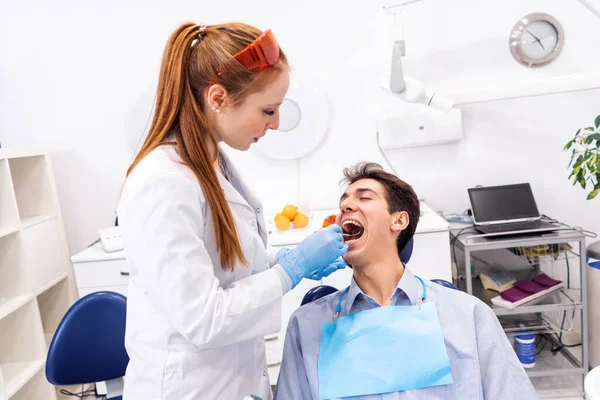 Счастливый человек во время обследования зубов в клинике — стоковое фото