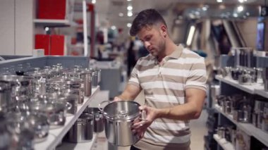 Alışveriş merkezinde yemek takımını seçen adam