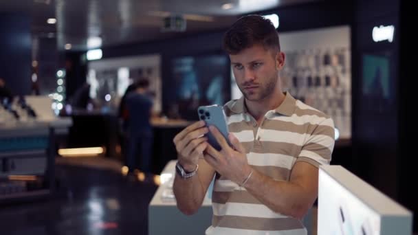 Hombre elegir el teléfono inteligente en la tienda moderna — Vídeos de Stock