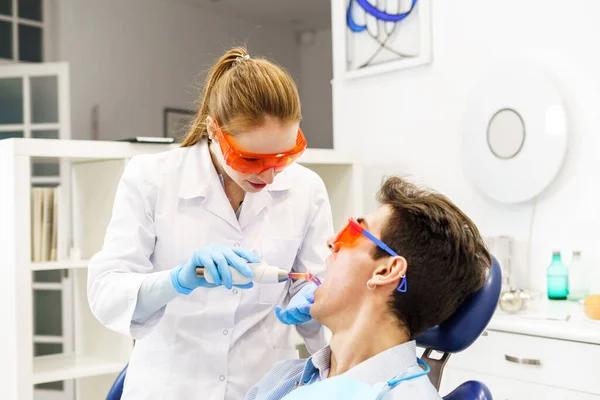Женщина исцеляет зубы пациентки в клинике — стоковое фото