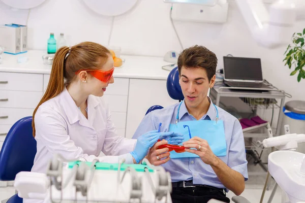 Female dentist giving goggles to male patient Royalty Free Stock Photos