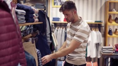 Odaklanmış adam dükkanda pantolon seçiyor.