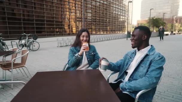 Wesoła, wieloetniczna para pijąca kawę w mieście — Wideo stockowe