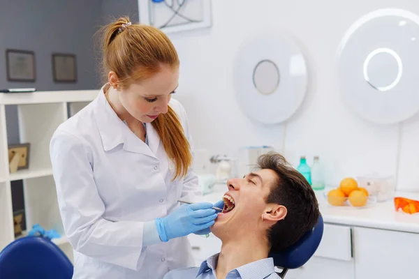 Женщина-дантист проводит обследование зубов в современном офисе — стоковое фото