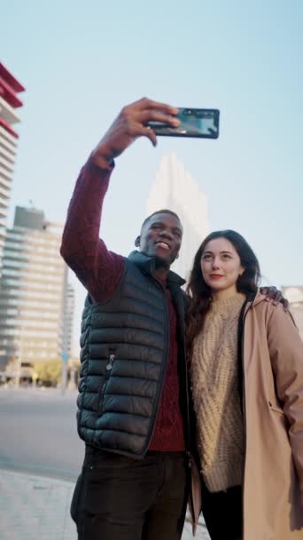 Alegre pareja multiétnica tomando selfies en la ciudad — Vídeos de Stock
