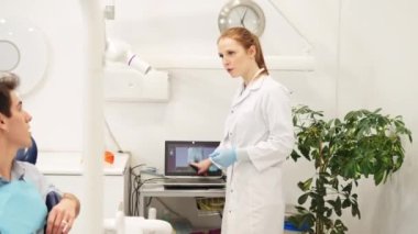 Diş hekimliği danışmanlığı. Kadın dişçi kontrol sırasında erkek hastayla diş röntgenini tartışıyor.