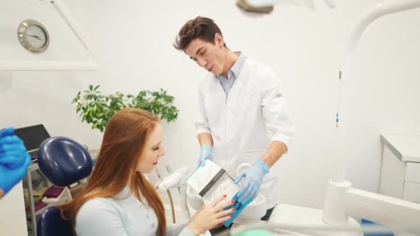 Professionele tandarts of orthodontist tonen uitlijnaars of kappa voor tanden uitlijning aan vrouwelijke patiënt — Stockvideo